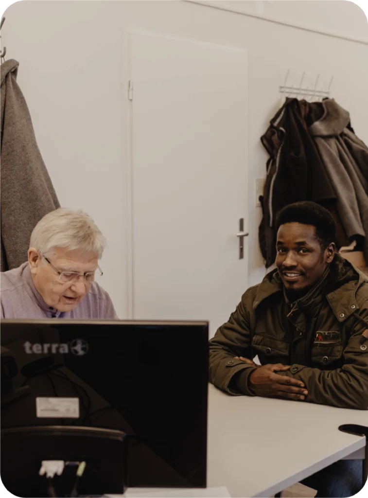 Mitarbeiter von FLUX Hildesheim am Schreibtisch mit einem lächelnden Mann