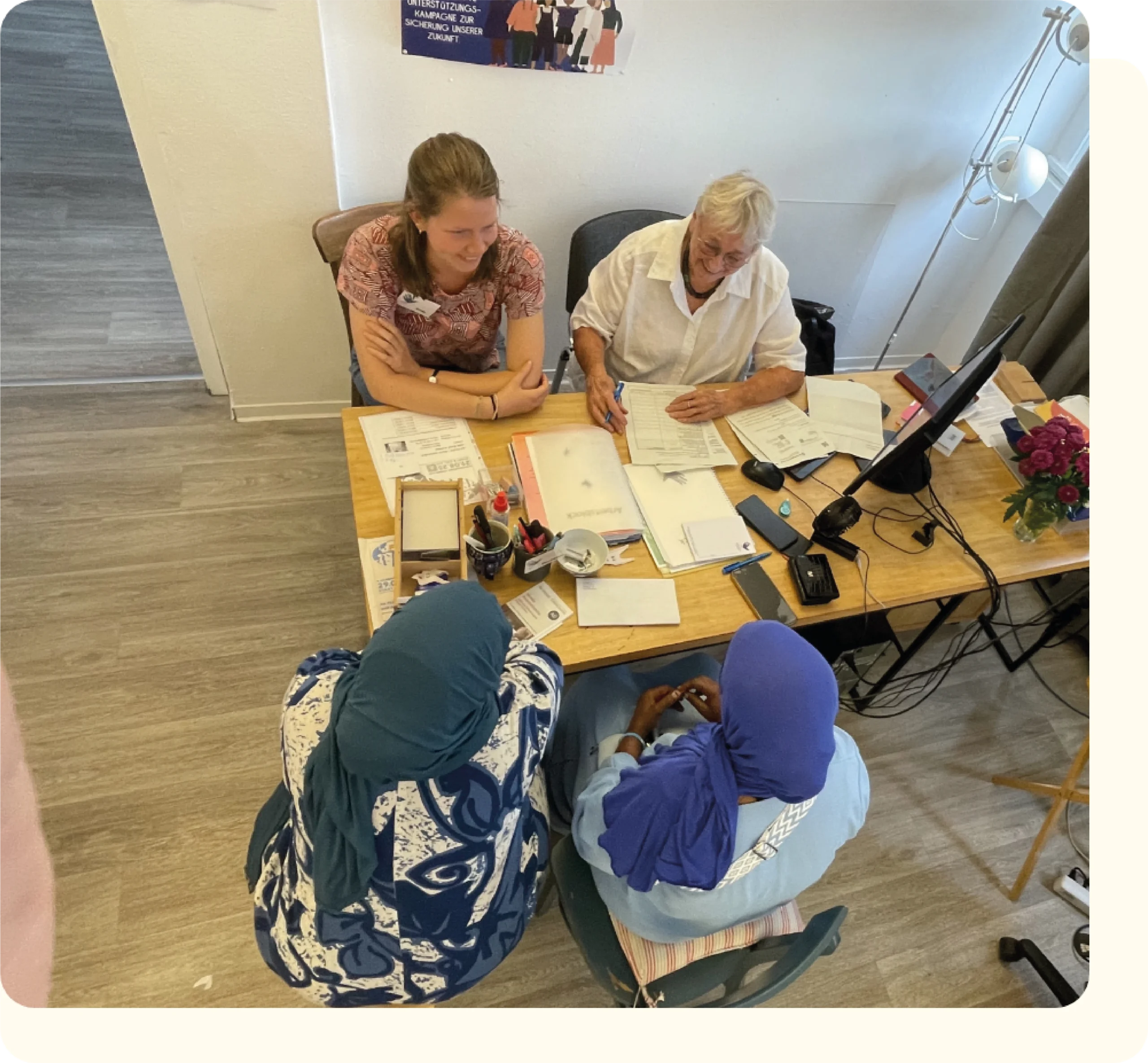 FLUX Mitarbeiterinnen am Schreibtisch im Gespräch mit 2 Flüchtlingen