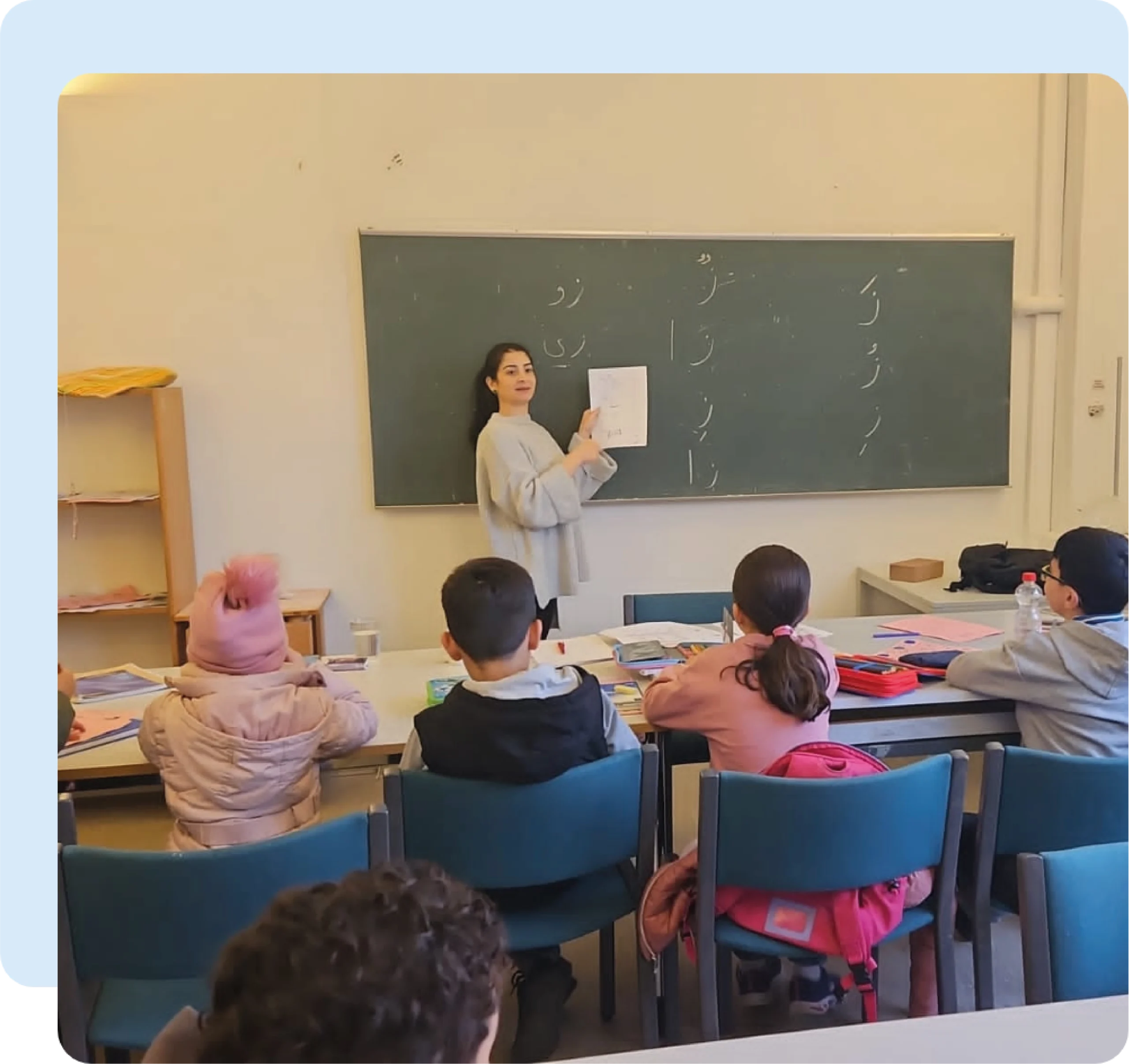 Arabisch-Lehrerin an einer Tafel stehend vor einer Klasse von Kindern.
