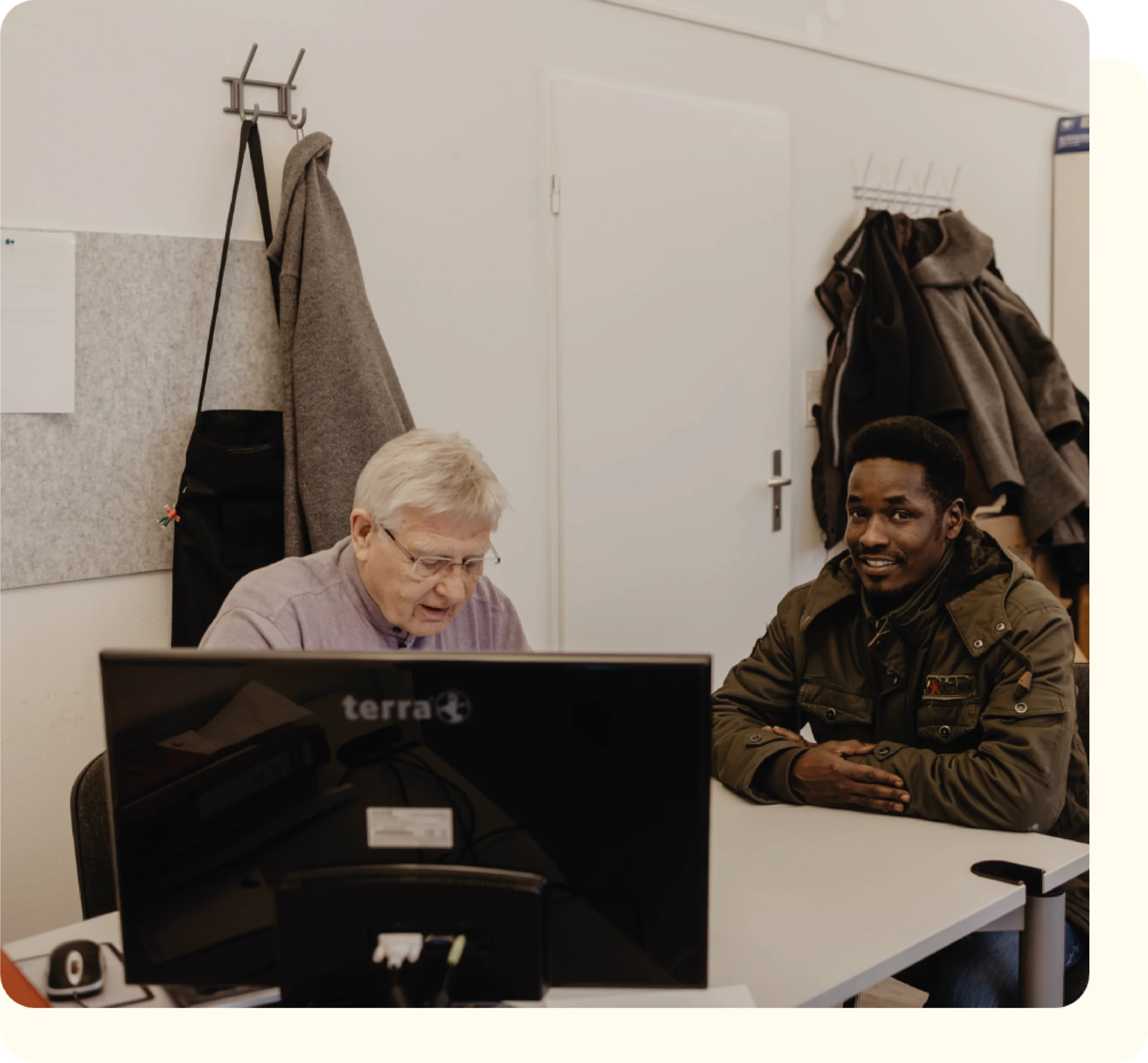 Mitarbeiter von FLUX Hildesheim am Schreibtisch mit einem lächelnden Mann