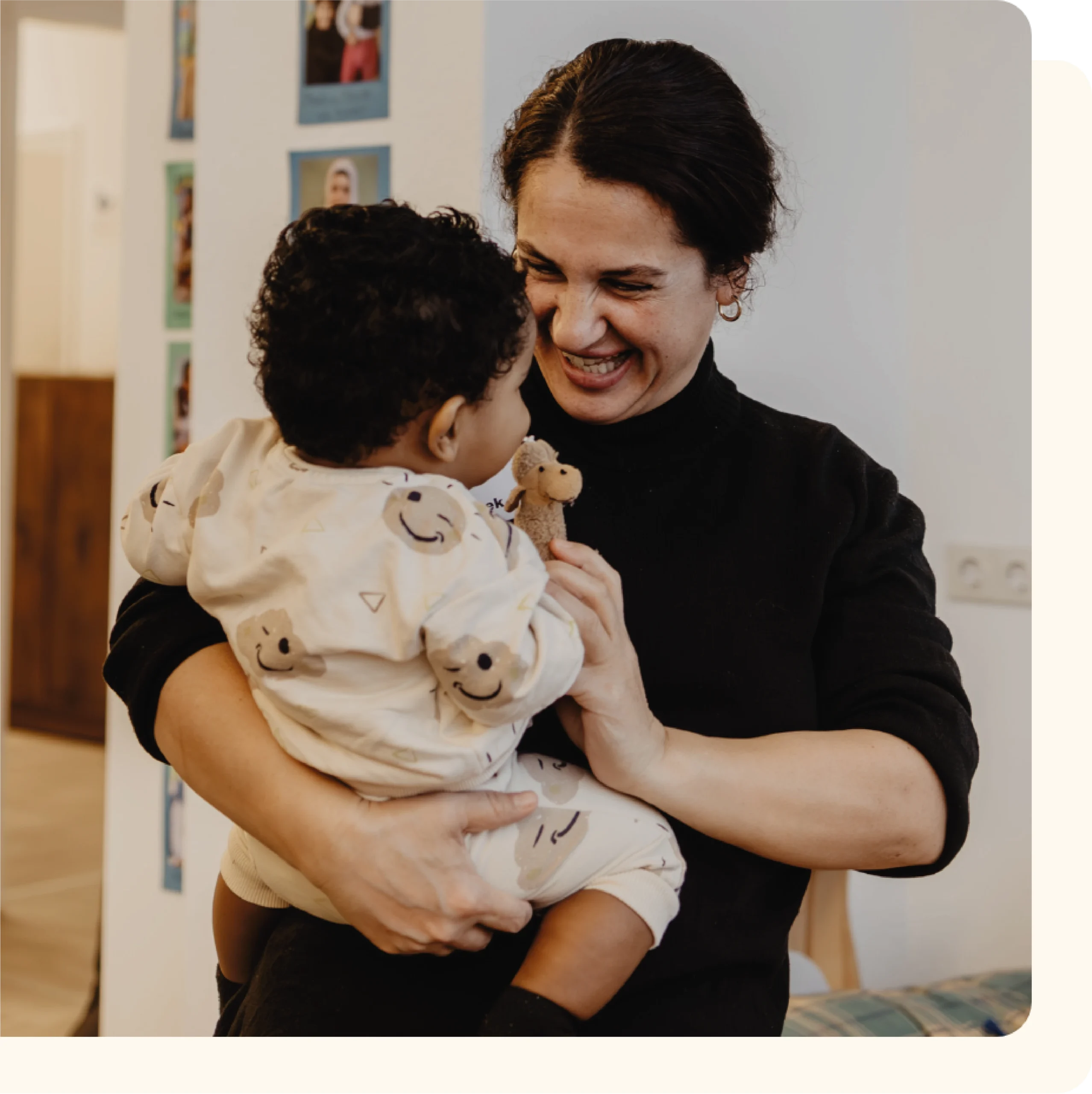 Lächelnde Mitarbeitern der FLUXi Kinderbetreuung beim spielen mit einem Kind auf ihrem Arm