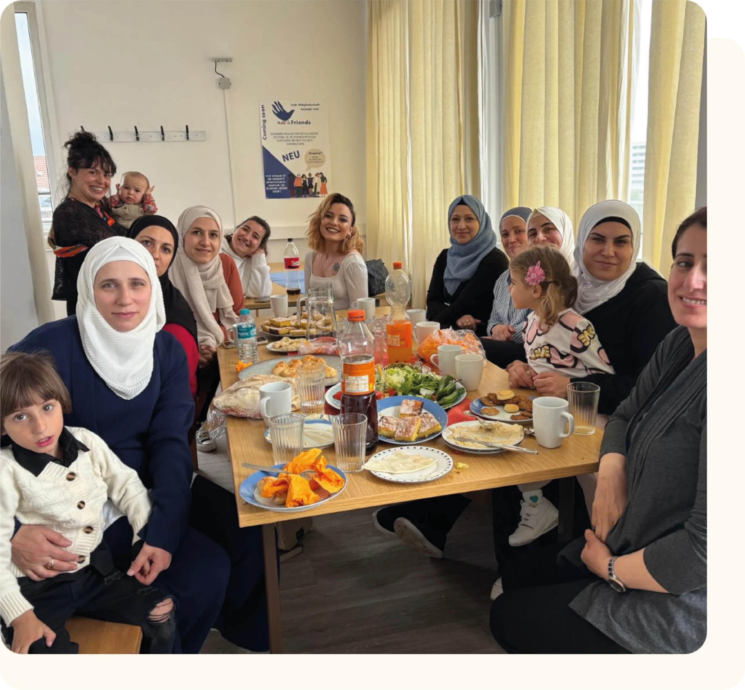 Eine Gruppe von Frauen, welche gemeinsam an einem gedeckten Tisch sitzen und lächeln. Bei einem Weltküche HILAR Event