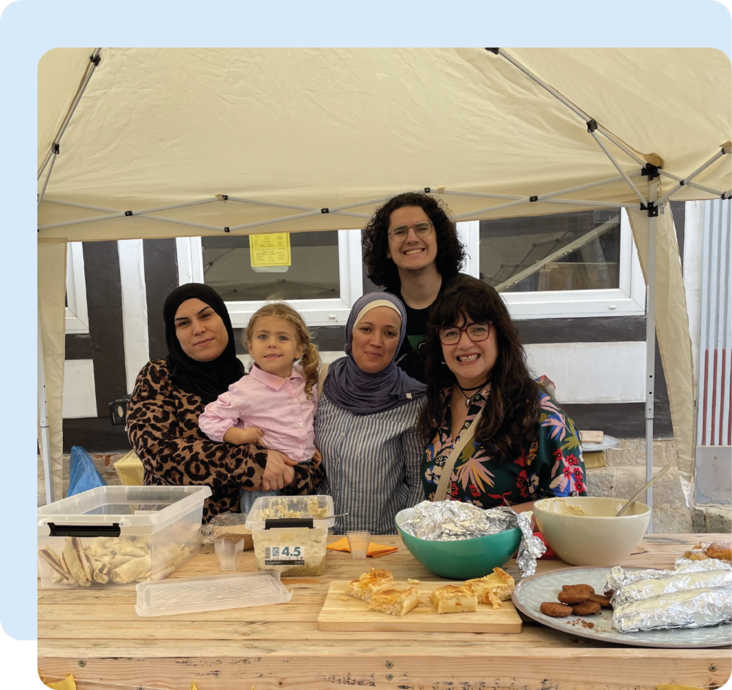 Eine Gruppe von Frauen, einem Mann und einem Kind an einem Tisch mit Essen sitzend.
